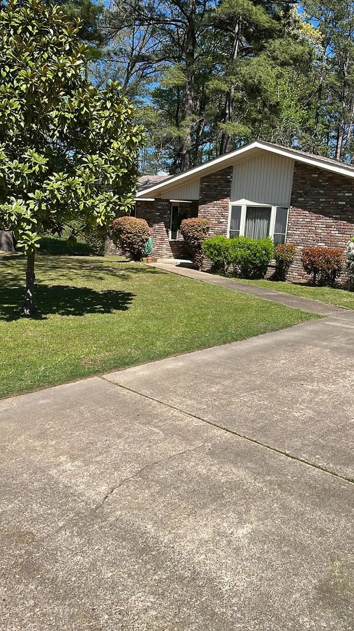 The client's own photograph of the red brick ranch with the gabled front, bay window, sculpted round shrubs, magnolia