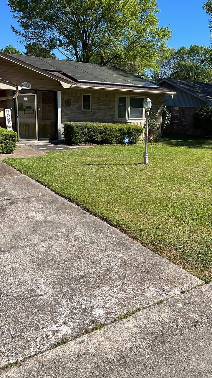 The client's own photograph of a tan brick ranch in a Little Rock neighbourhood, foundation hedges trimmed to a clean line